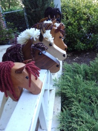 10 hobby horses lined up in a row hand made from natural wood