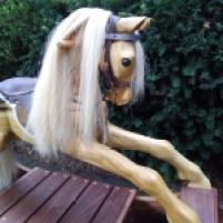 wooden rocking horse showing a view of the leather bridle with sparkly silver brow band and real bit. Also shows real horse hair mane and glass eye.