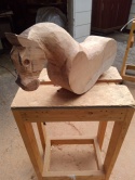 rough carving done on wood rocking horse body, neck and face, shown placed on wood work table